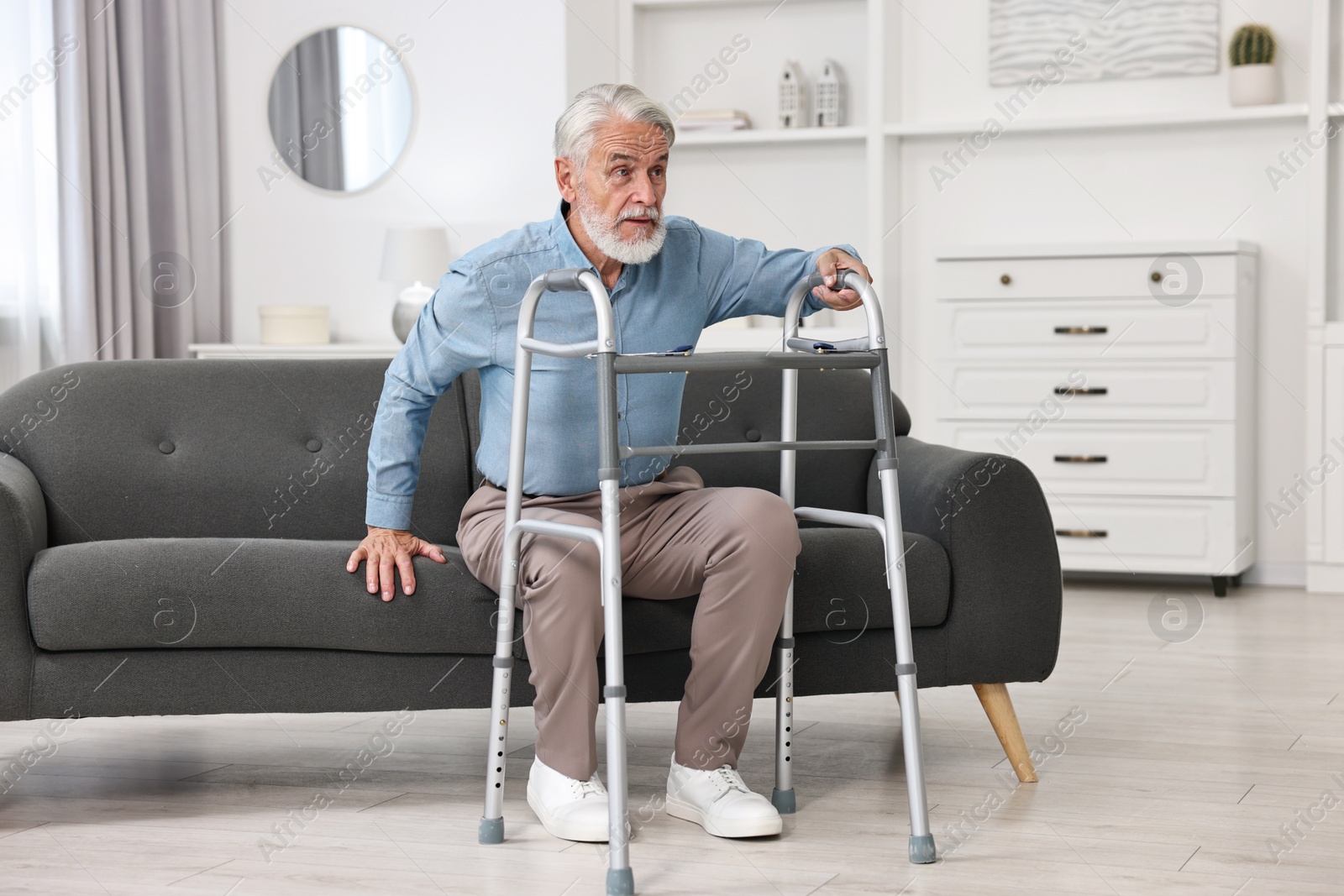 Photo of Senior man with walking frame on sofa at home