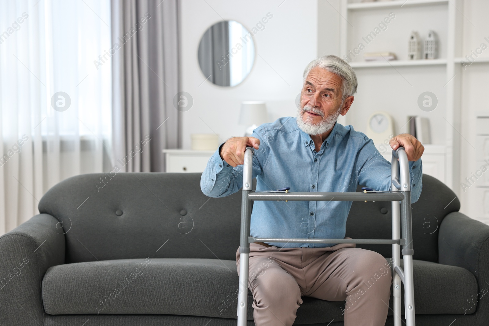 Photo of Senior man with walking frame on sofa at home