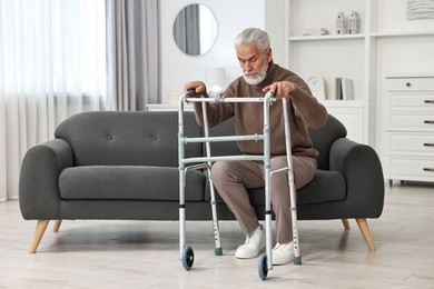 Photo of Senior man with walking frame on sofa at home