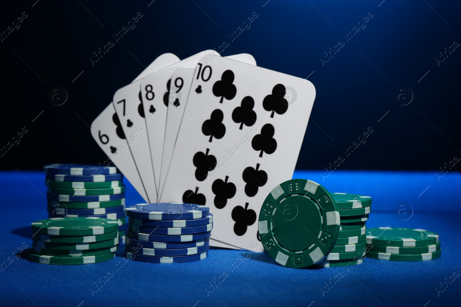 Photo of Poker chips and playing cards on blue table