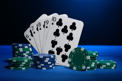 Poker chips and playing cards on blue table