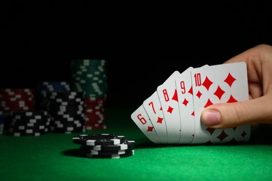 Photo of Woman with playing cards and poker chips at green table, closeup. Space for text