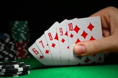 Photo of Woman with playing cards and poker chips at green table, closeup