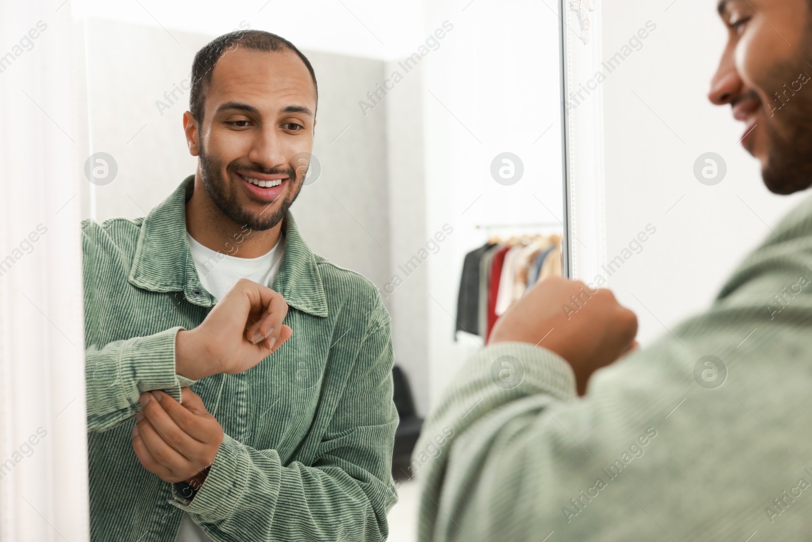 Photo of Smiling man dressing near mirror at home