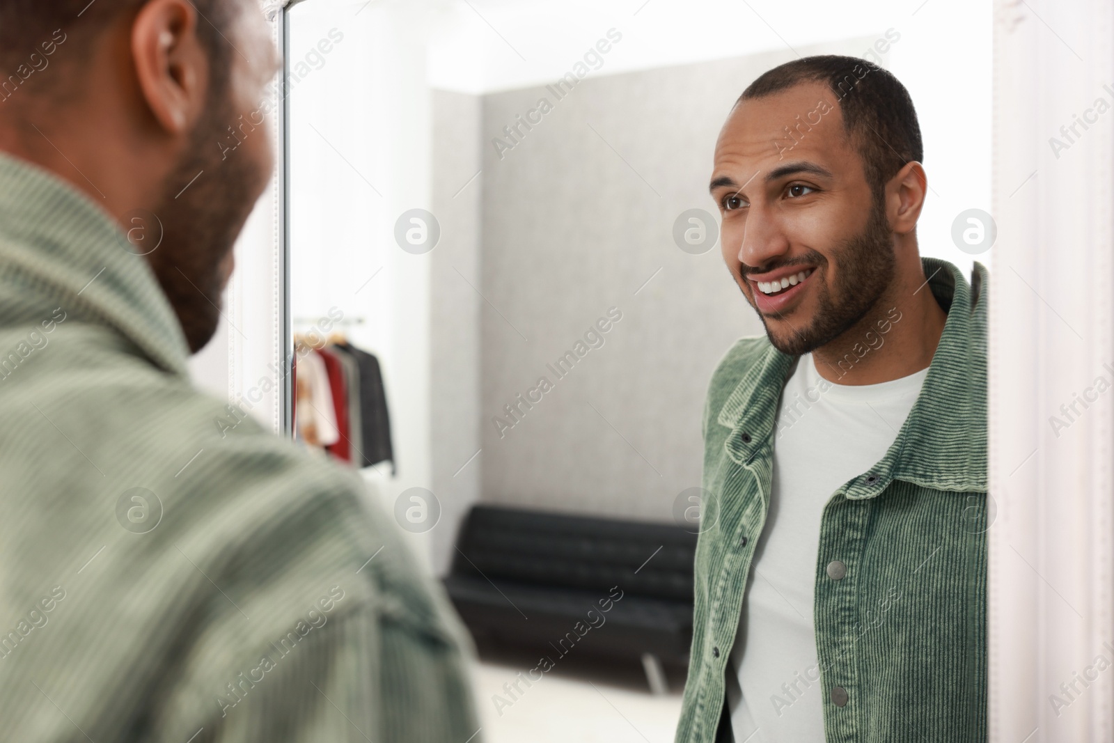 Photo of Smiling man looking at mirror at home