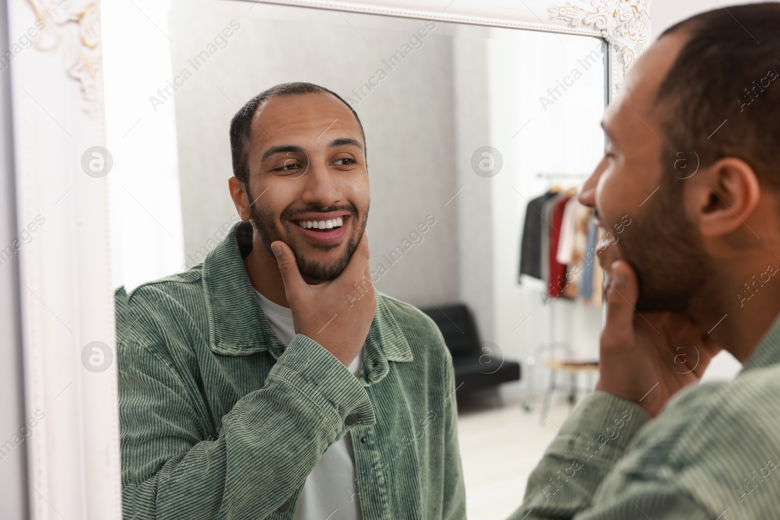 Photo of Smiling man looking at mirror at home