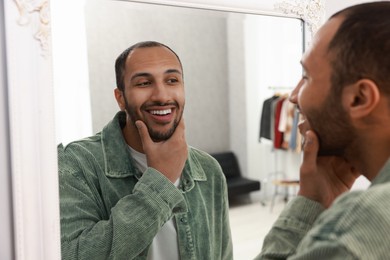 Photo of Smiling man looking at mirror at home