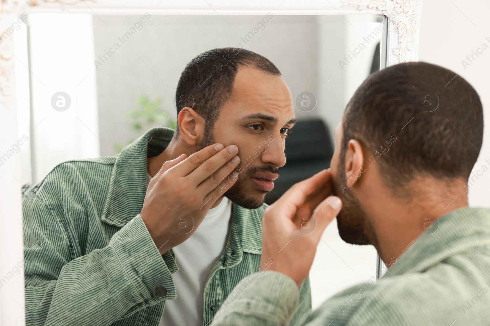 Photo of Worried man looking at mirror at home