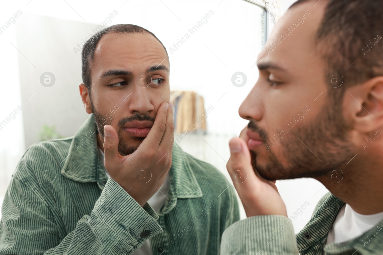 Photo of Worried man looking at mirror at home