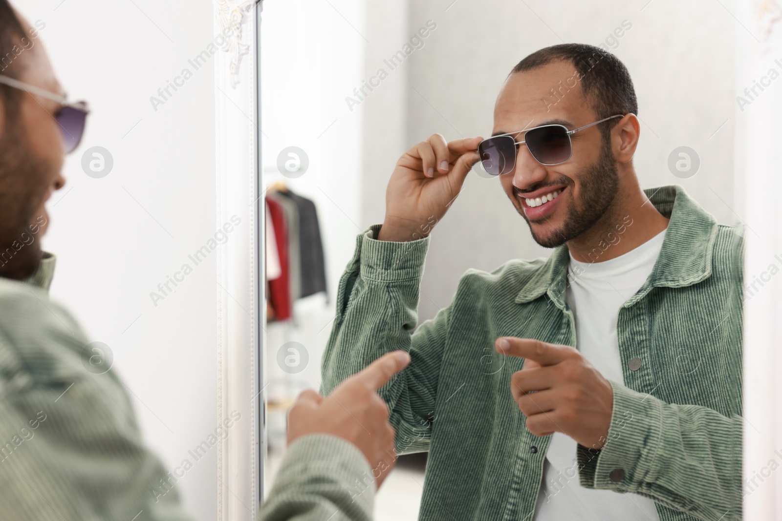 Photo of Smiling man looking at mirror at home