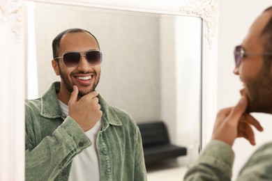 Photo of Smiling man looking at mirror at home