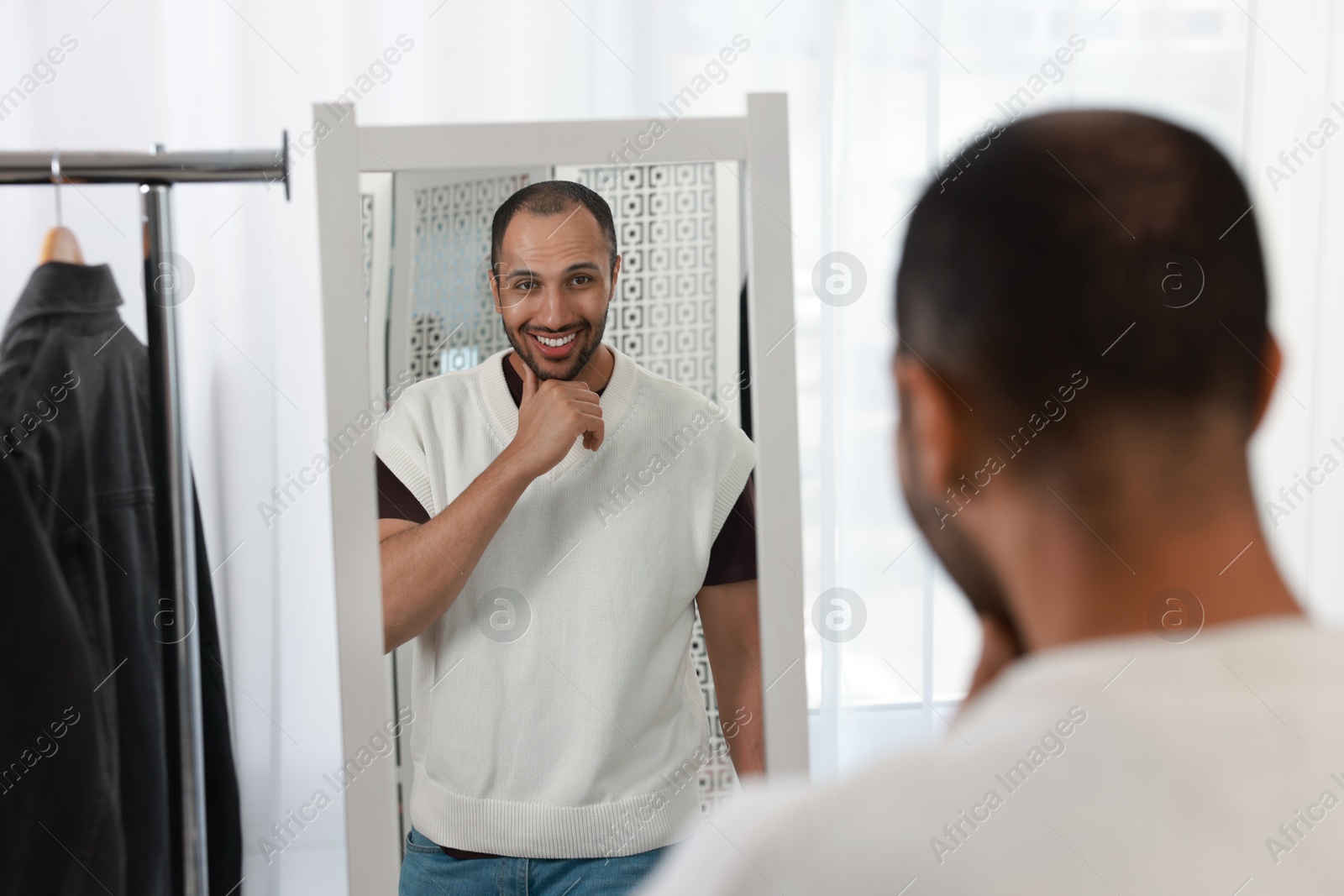 Photo of Smiling man looking at mirror at home