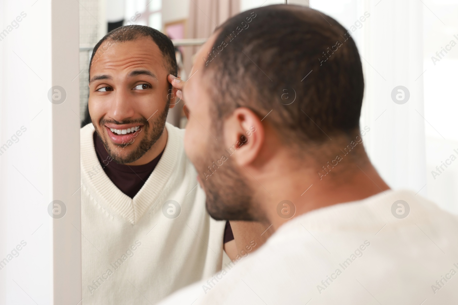 Photo of Smiling man looking at mirror at home