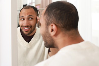 Photo of Smiling man looking at mirror at home