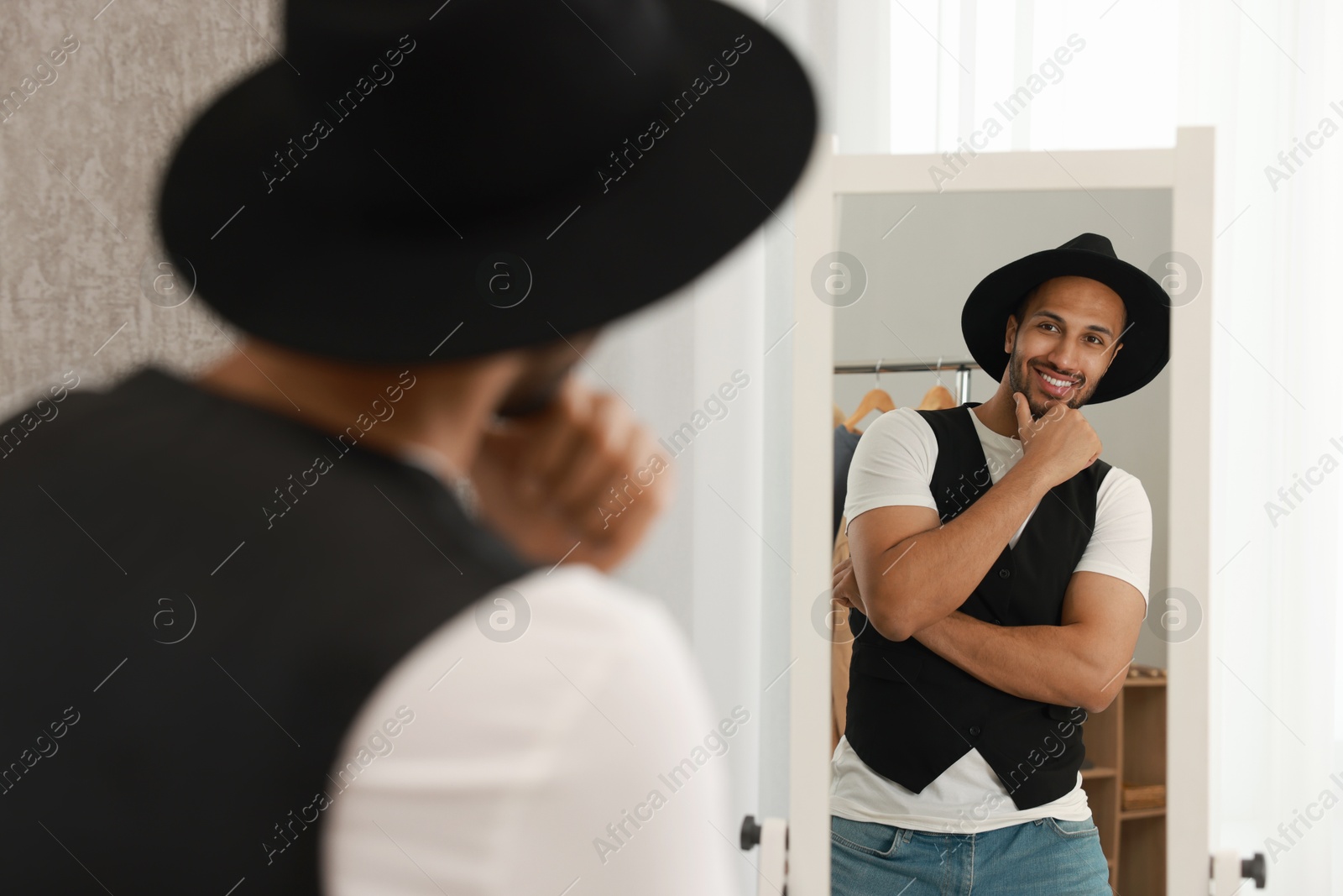 Photo of Smiling man looking at mirror at home