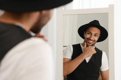 Photo of Smiling man looking at mirror at home