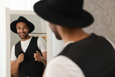 Photo of Smiling man looking at mirror at home