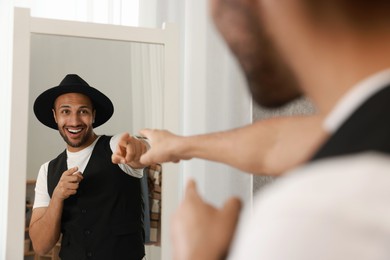 Photo of Smiling man looking at mirror at home