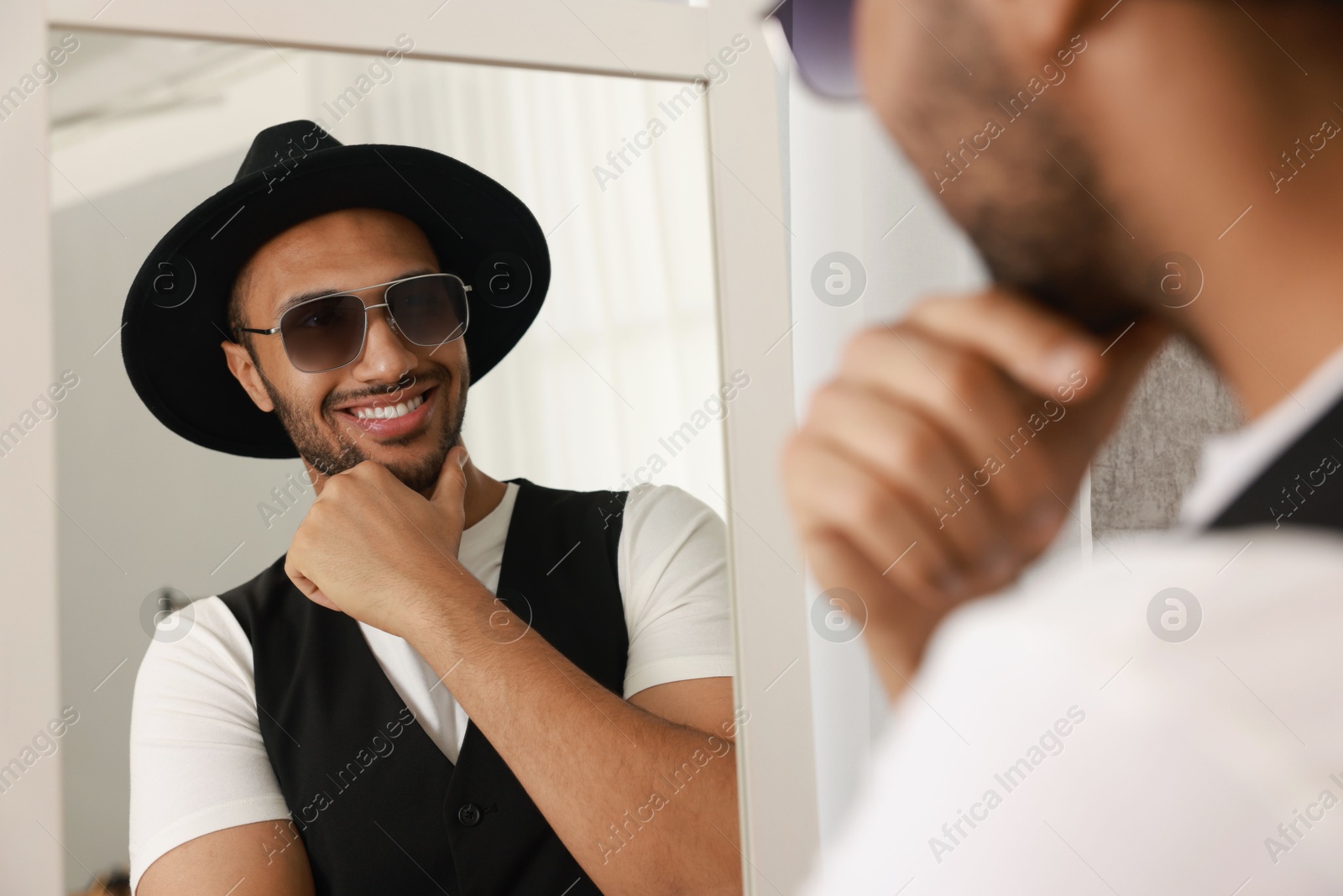 Photo of Smiling man looking at mirror at home