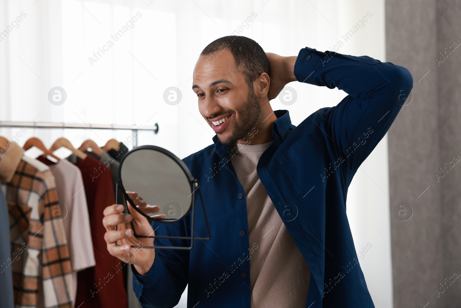 Photo of Smiling man looking at mirror at home