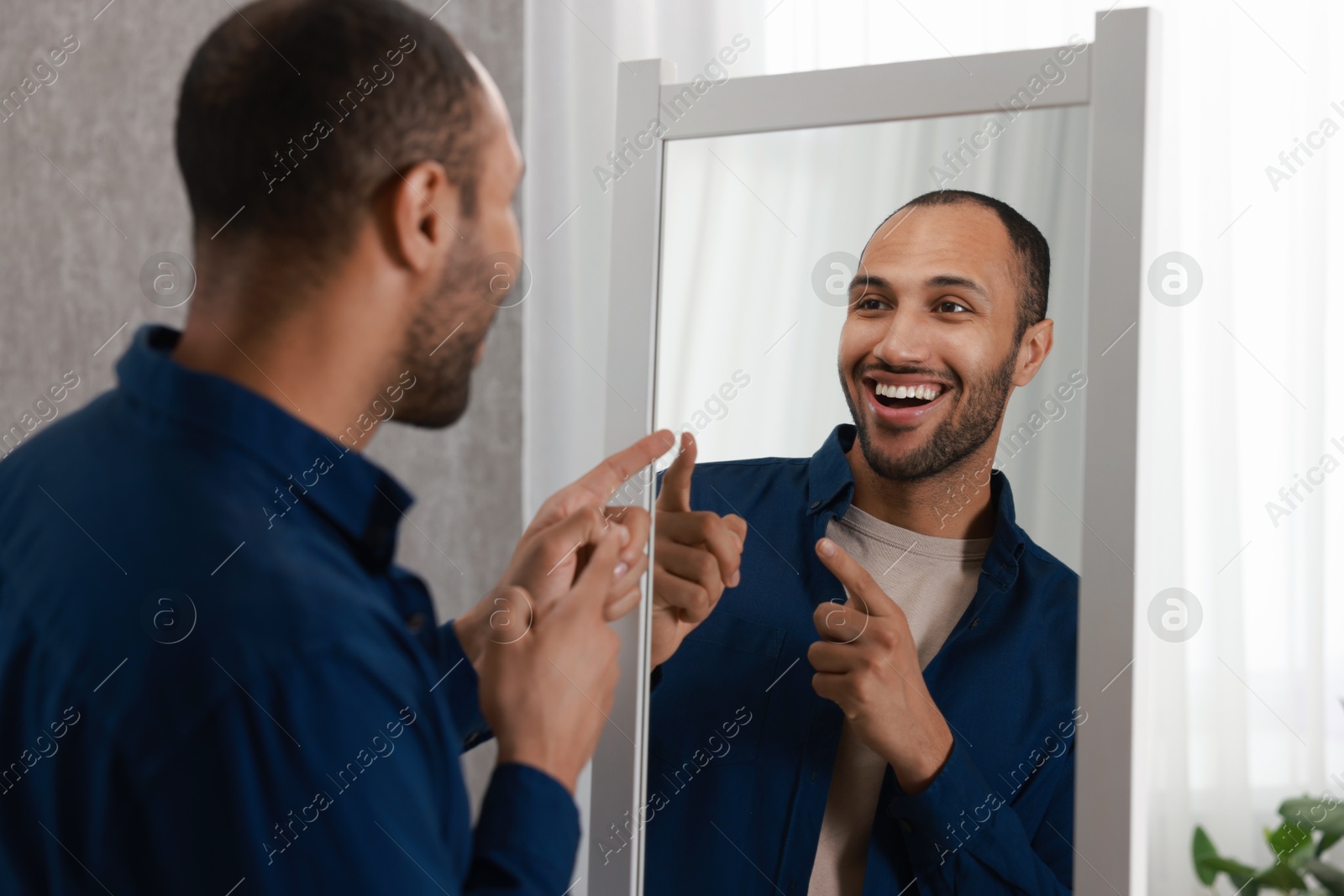 Photo of Smiling man looking at mirror at home