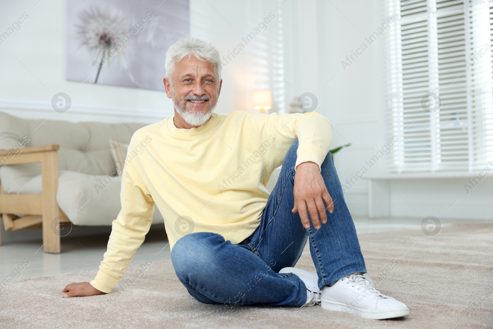 Photo of Smiling senior man sitting on floor at home