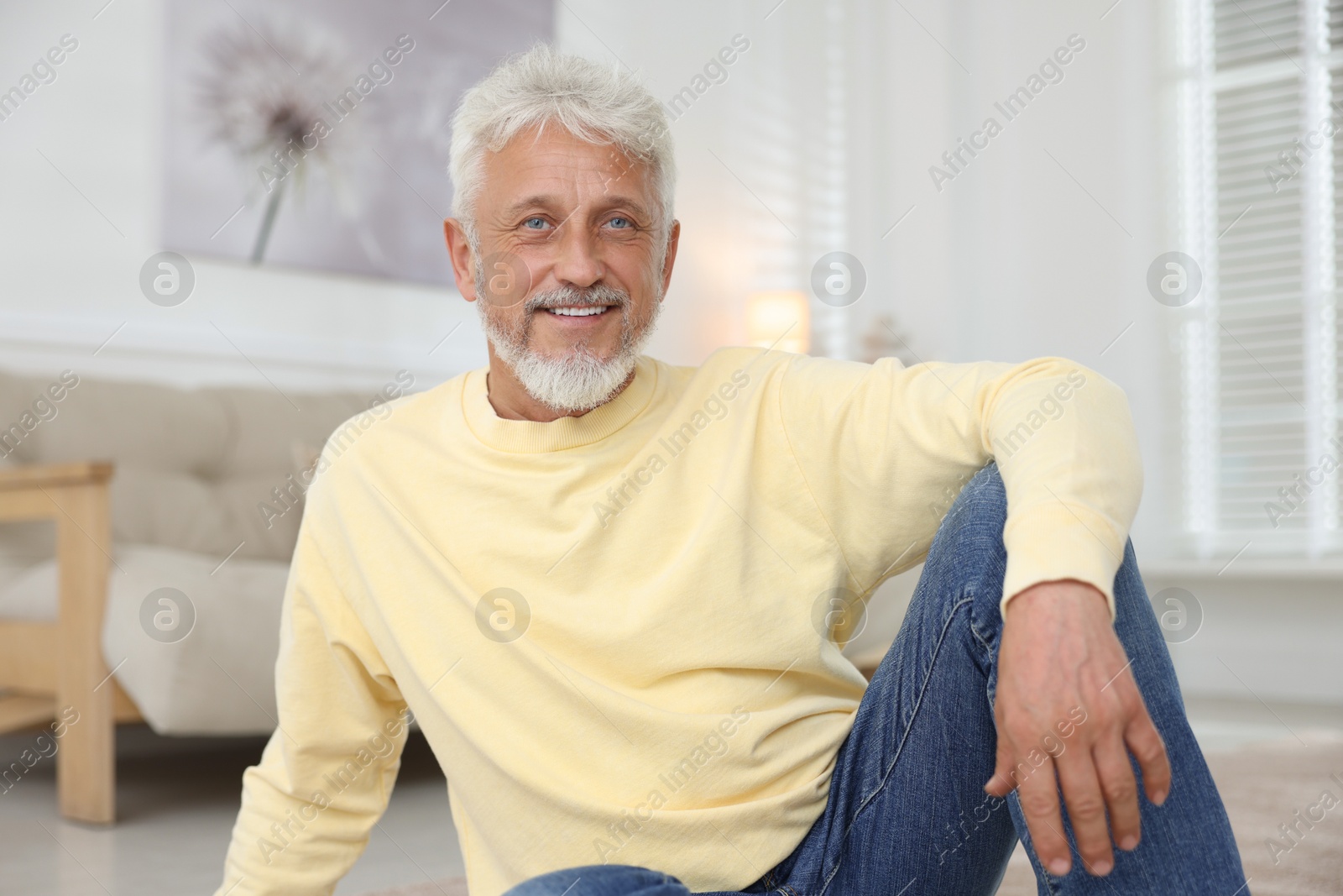 Photo of Smiling senior man sitting on floor at home