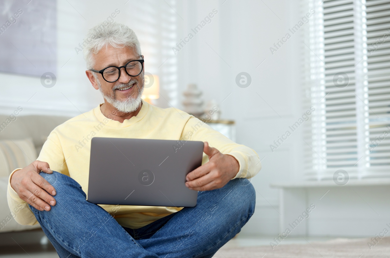 Photo of Senior man using laptop on floor at home, space for text