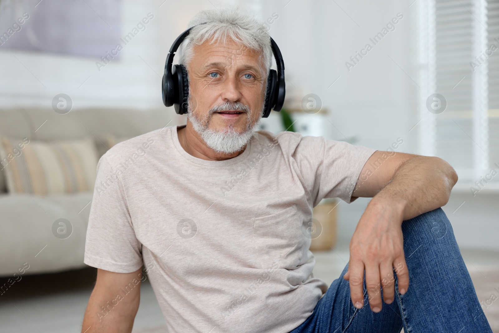 Photo of Senior man in headphones listening to music at home