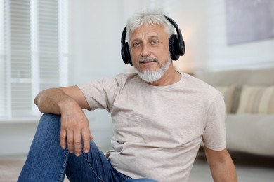 Photo of Senior man in headphones listening to music at home