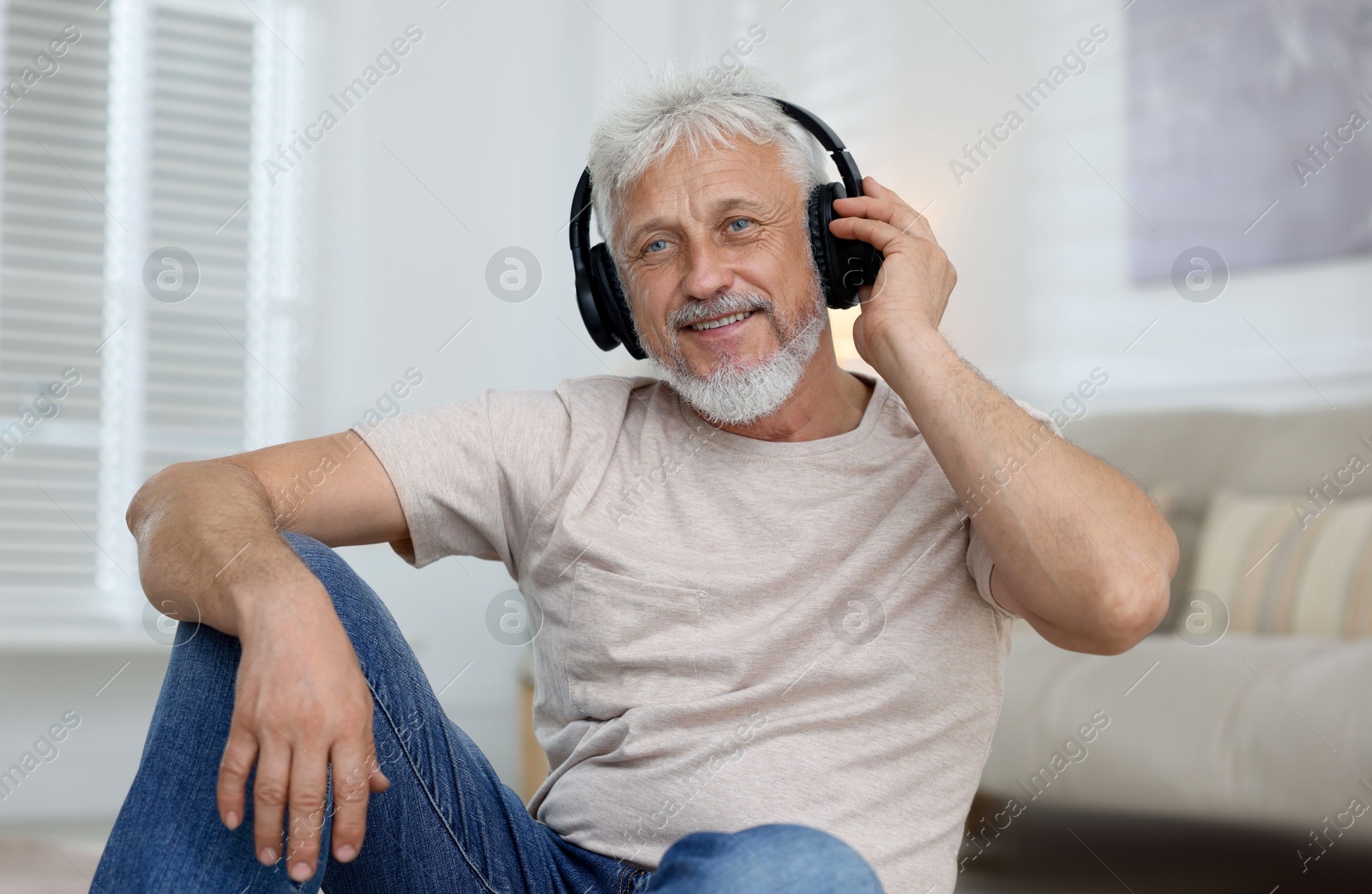 Photo of Senior man in headphones listening to music at home