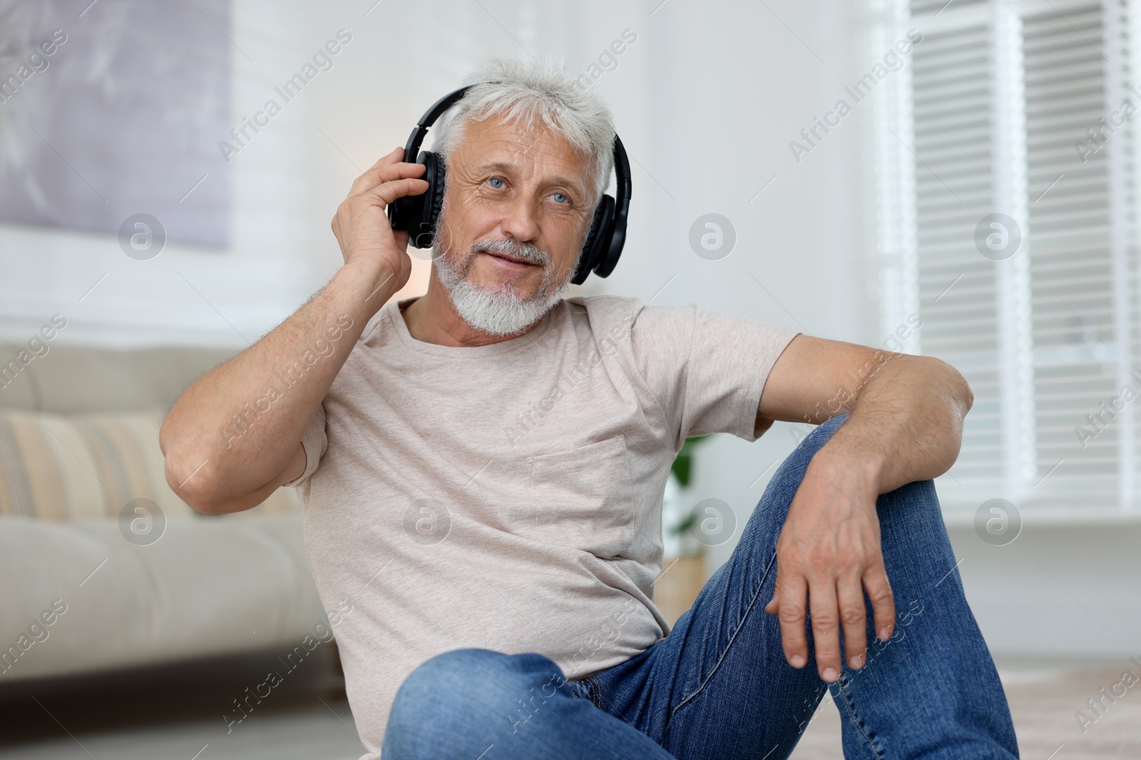 Photo of Senior man in headphones listening to music at home