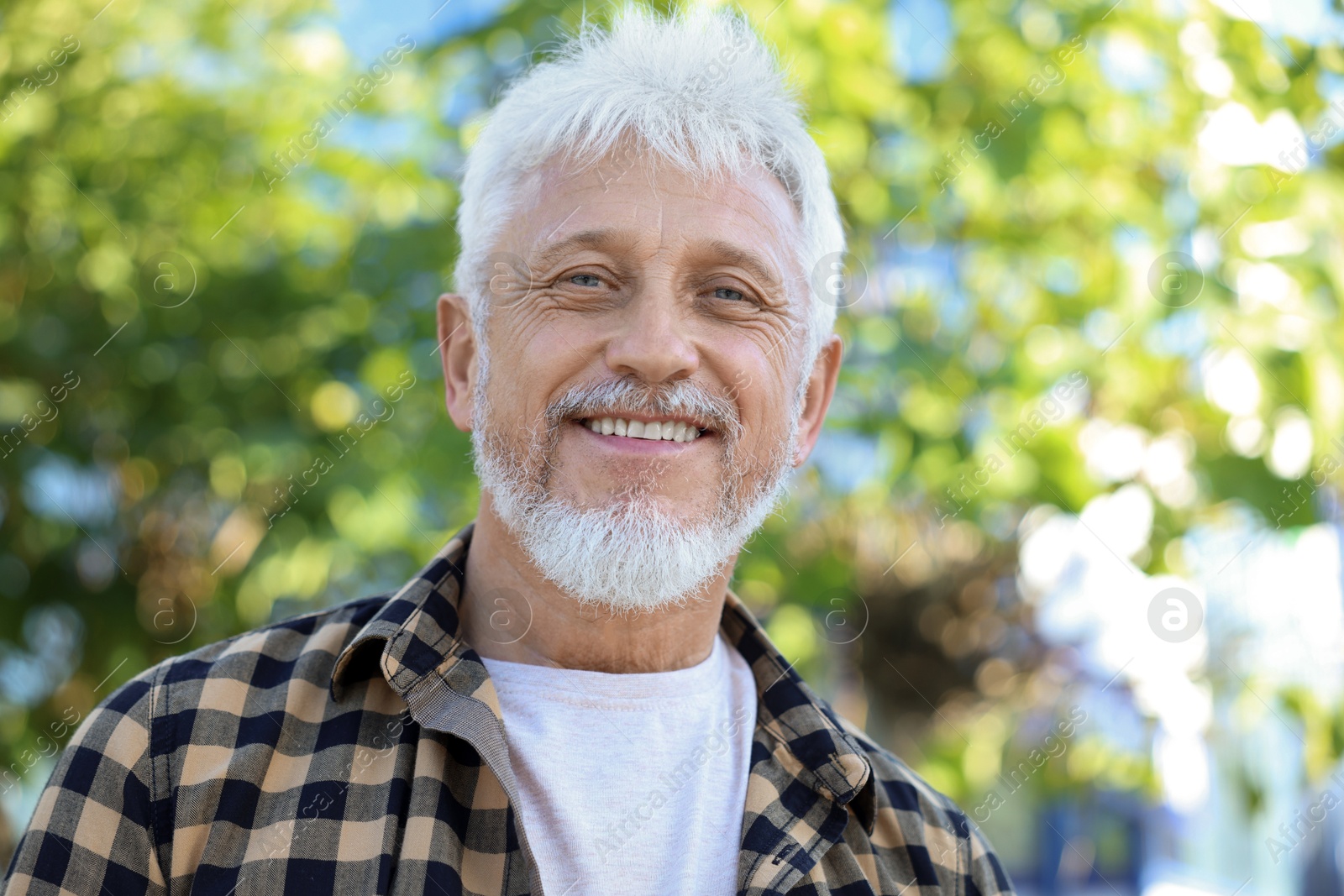 Photo of Portrait of smiling senior man in checkered shirt outdoors