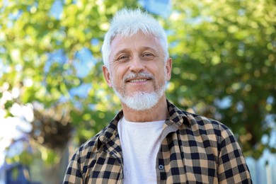 Photo of Portrait of smiling senior man in checkered shirt outdoors