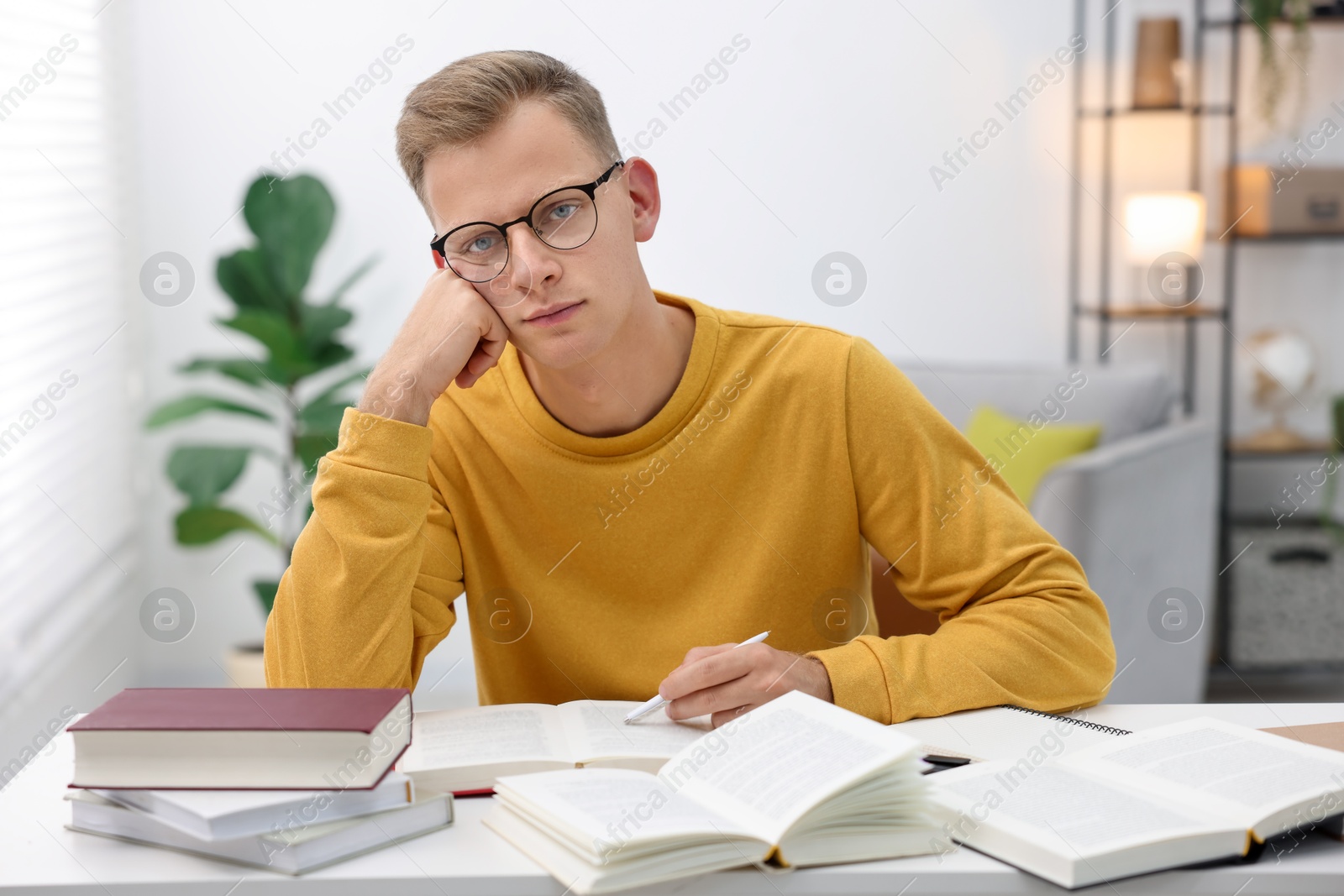 Photo of Preparing for exam. Student with books at table indoors