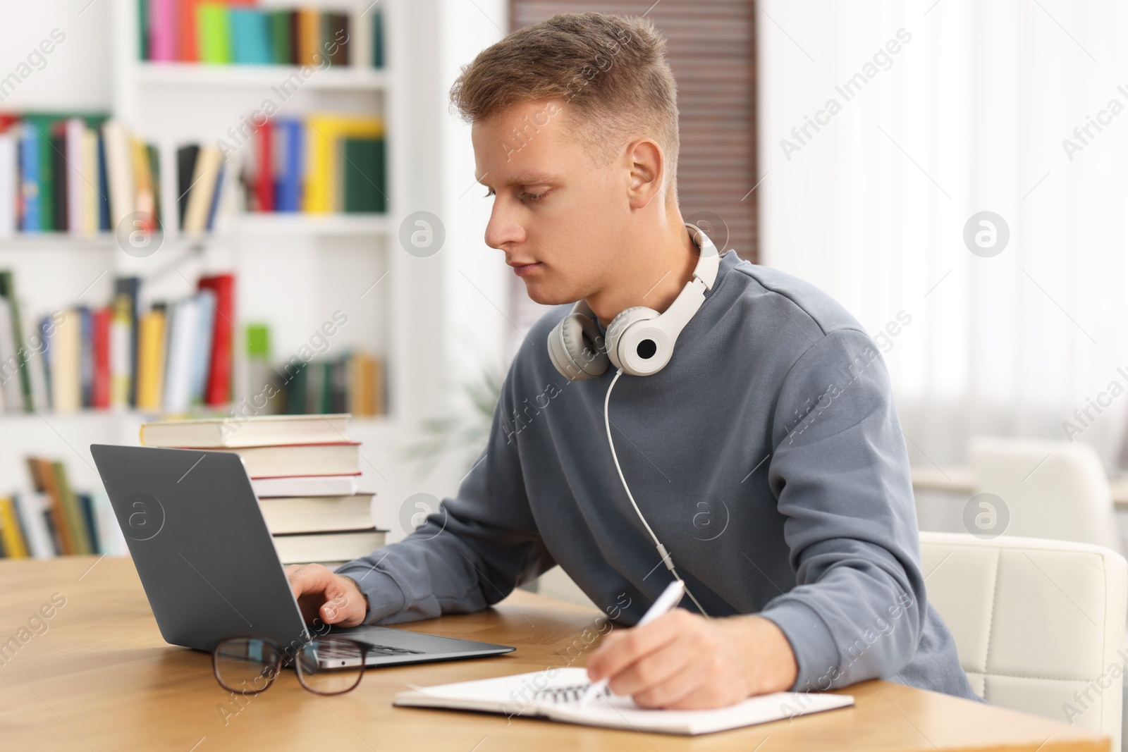 Photo of Student preparing for exam with laptop at table indoors