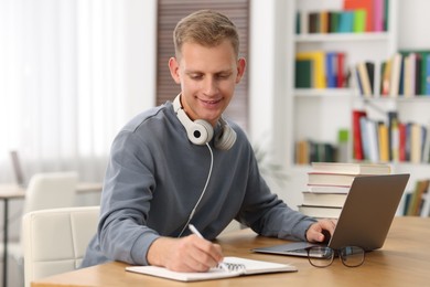 Photo of Student preparing for exam with laptop at table indoors