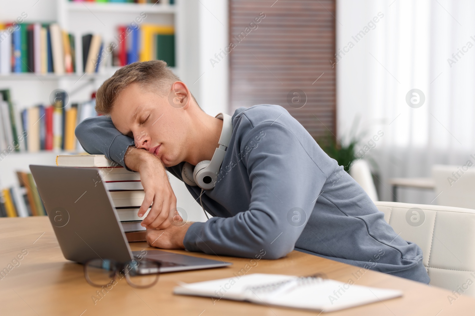 Photo of Preparing for exam. Tired student sleeping among books at table indoors