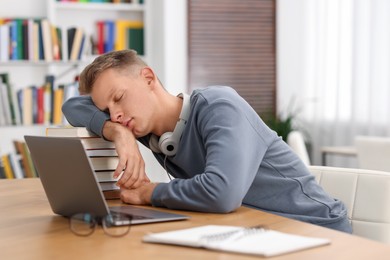 Photo of Preparing for exam. Tired student sleeping among books at table indoors