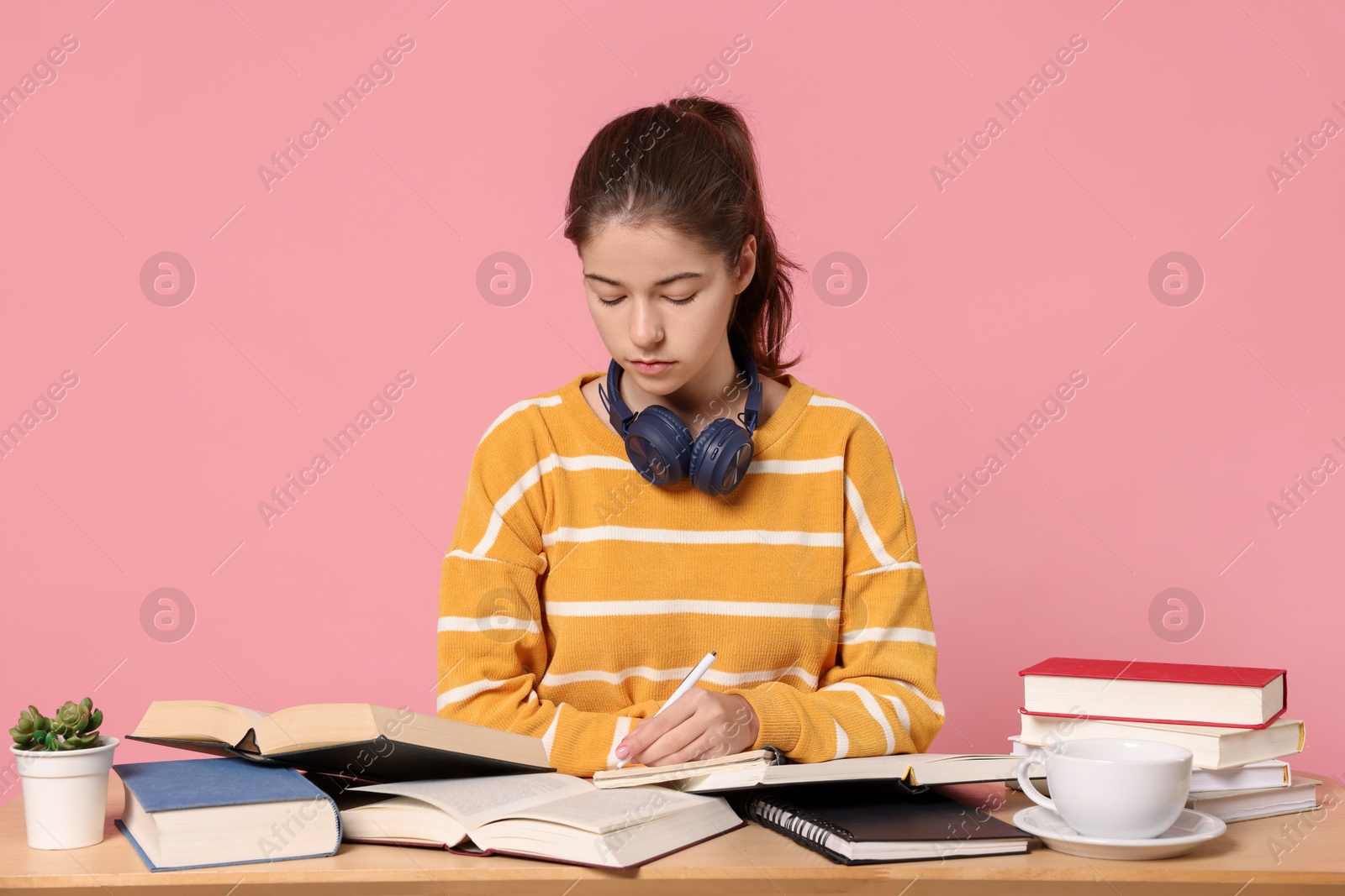 Photo of Student preparing for exam at table against pink background