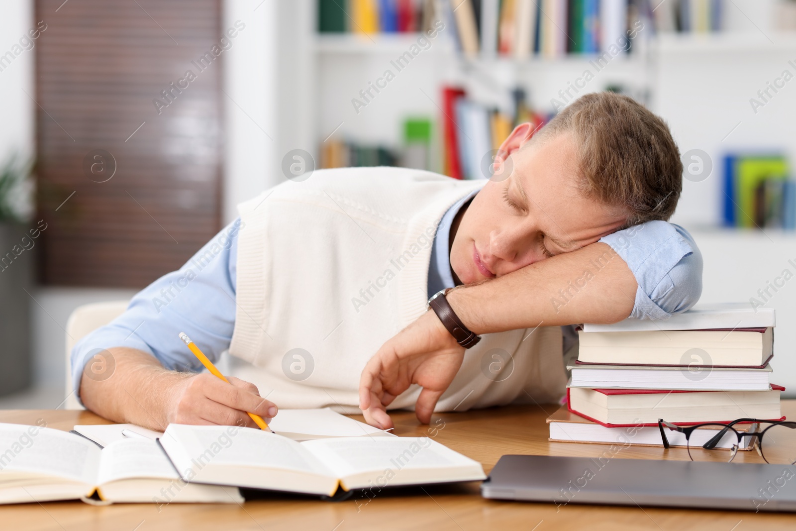 Photo of Preparing for exam. Tired student sleeping among books at table indoors