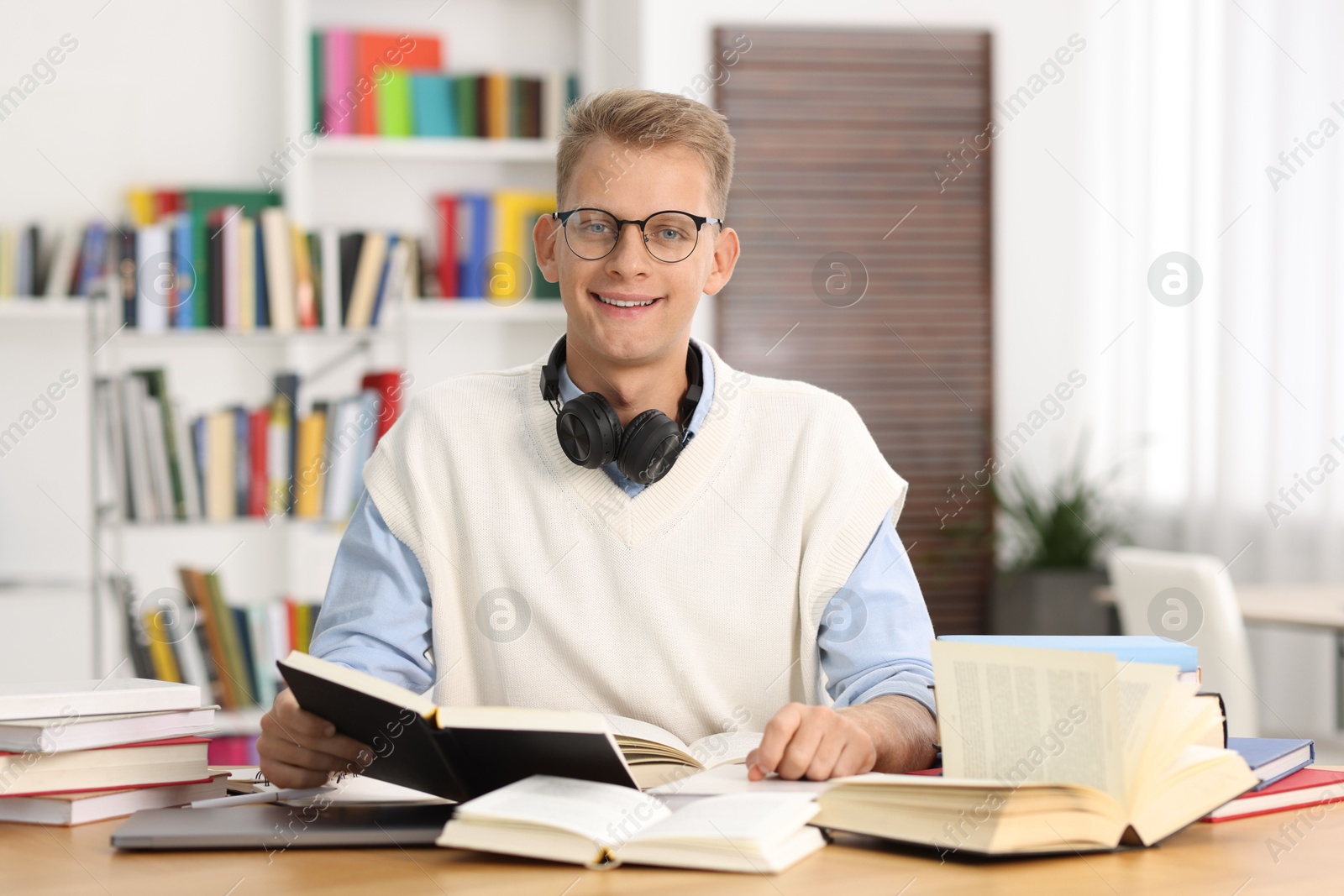 Photo of Preparing for exam. Student with books at table indoors