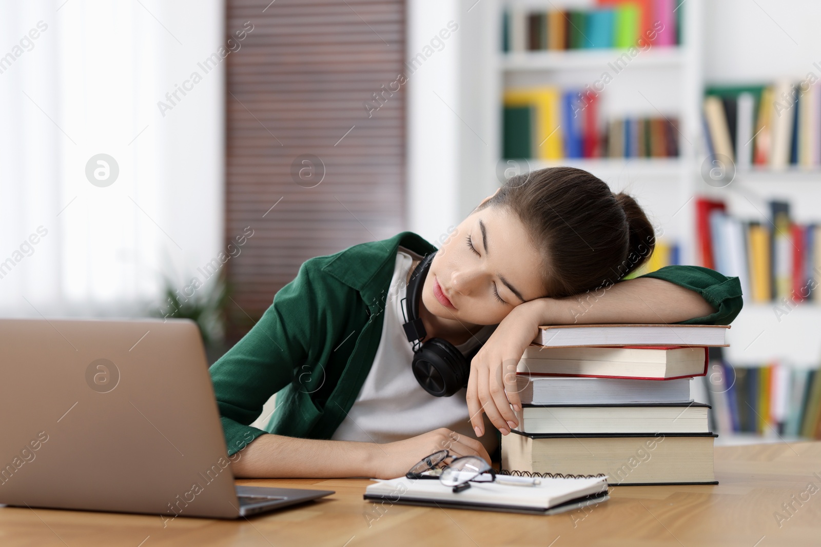 Photo of Preparing for exam. Tired student sleeping among books at table indoors