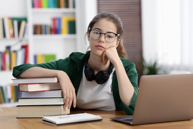 Photo of Preparing for exam. Student with laptop and books at table indoors