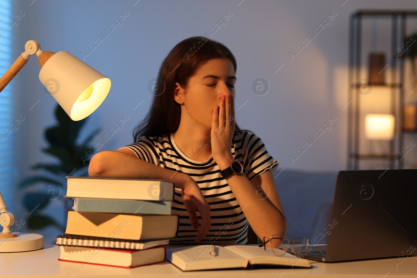 Photo of Preparing for exam. Tired student with books at table indoors