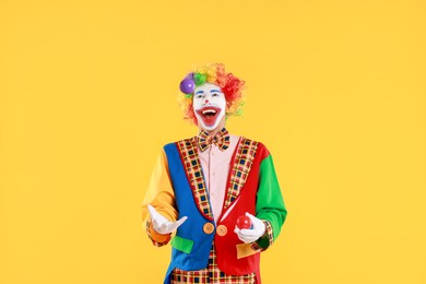 Photo of Happy clown juggling balls on yellow background