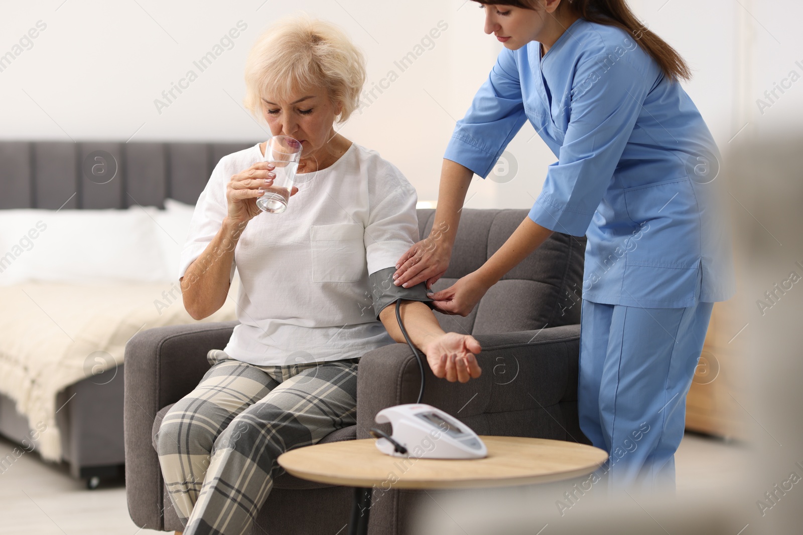 Photo of Nurse measuring senior woman's blood pressure at home