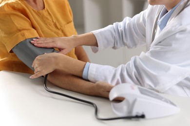 Photo of Doctor measuring senior woman's blood pressure during appointment in hospital, closeup