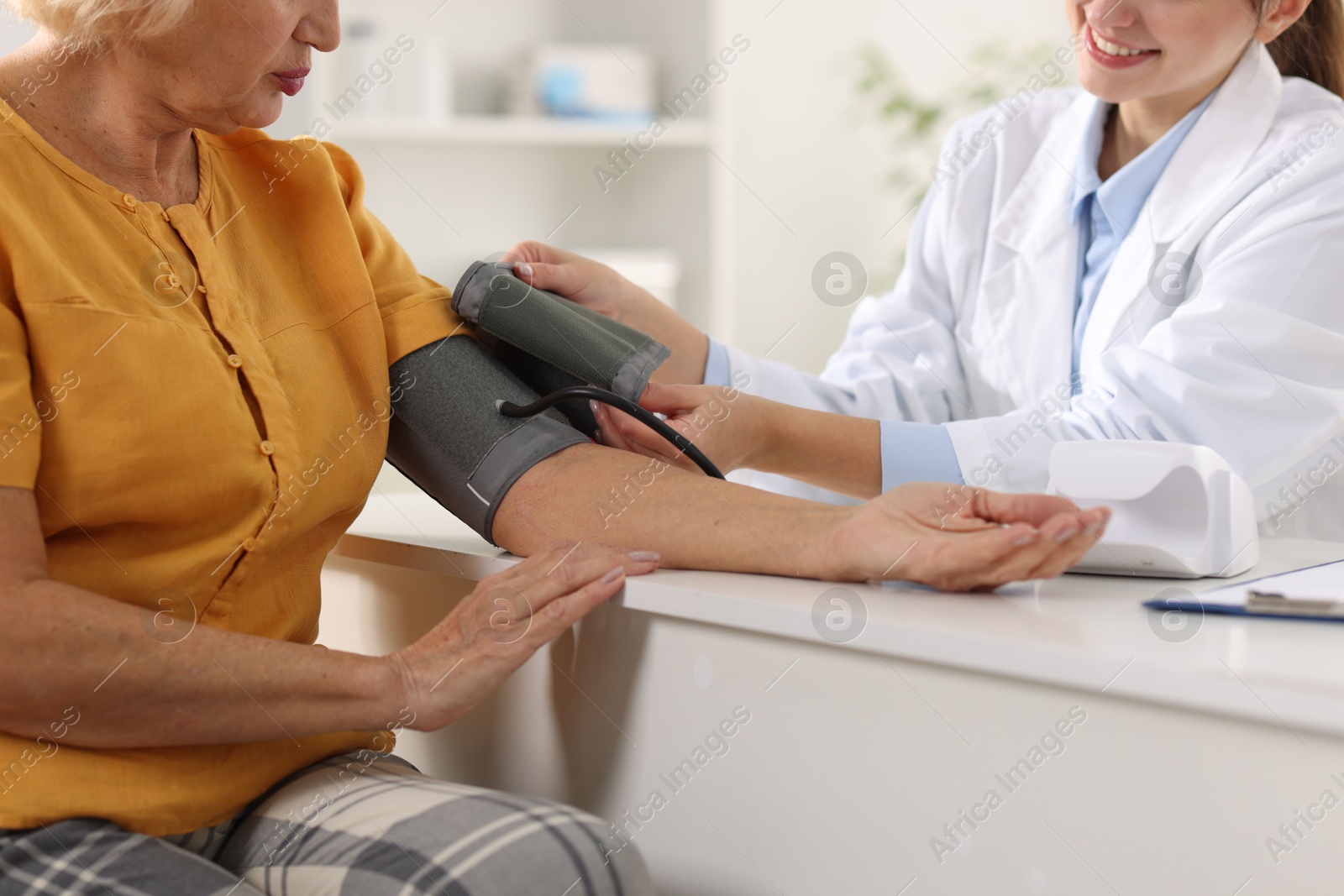 Photo of Doctor measuring senior woman's blood pressure during appointment in hospital, closeup