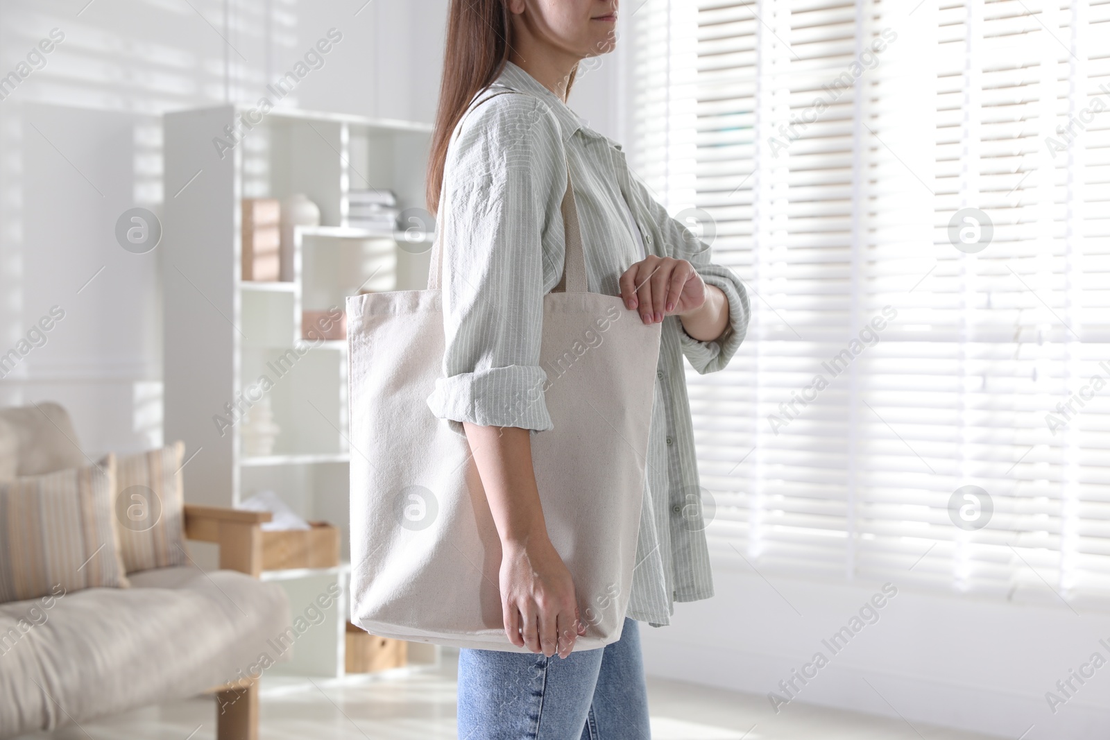 Photo of Woman with blank shopper bag indoors, closeup. Mockup for design